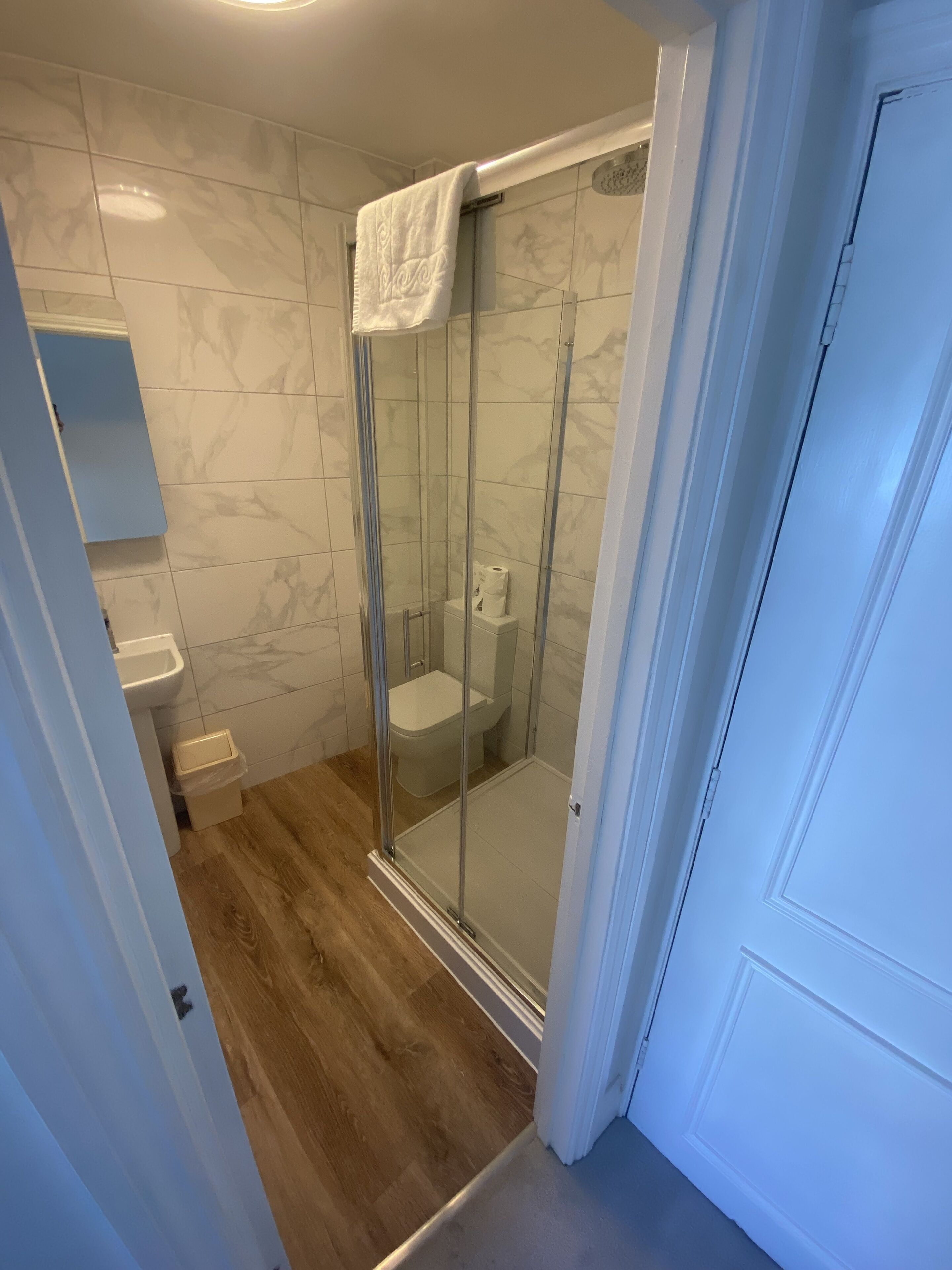 Une salle de bain avec une douche à parois de verre, des toilettes et un lavabo.