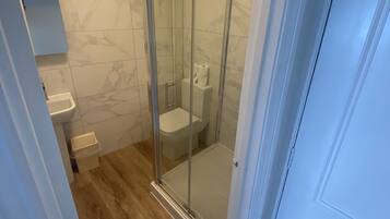 Une salle de bain avec une douche à parois de verre, des toilettes et un lavabo.