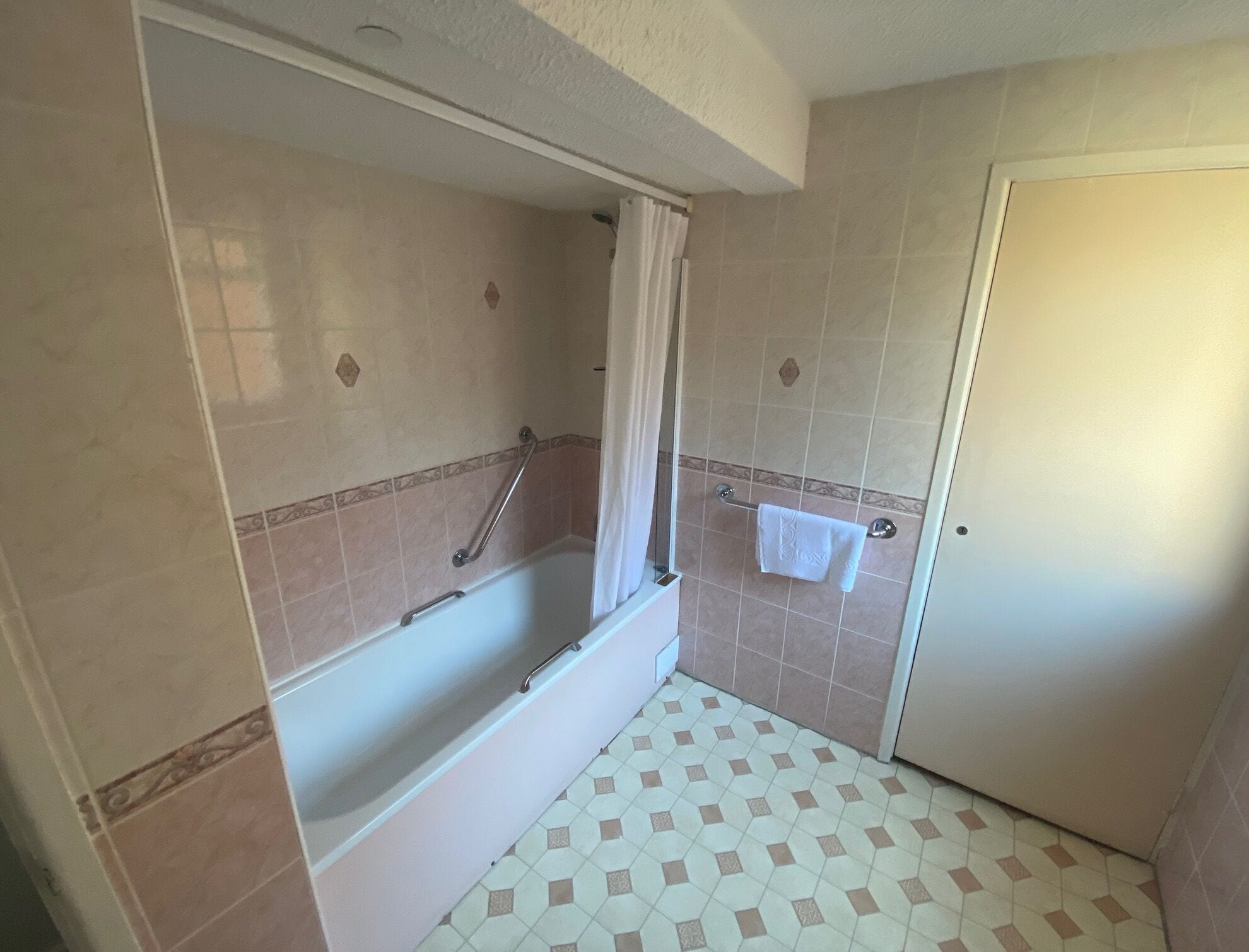 Een badkamer met een bad, een douche en een deur.
