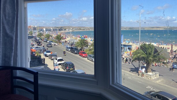 A view from a window overlooking a busy street with a beach and ocean in the background. - Fairhaven Hotel (Weymouth)