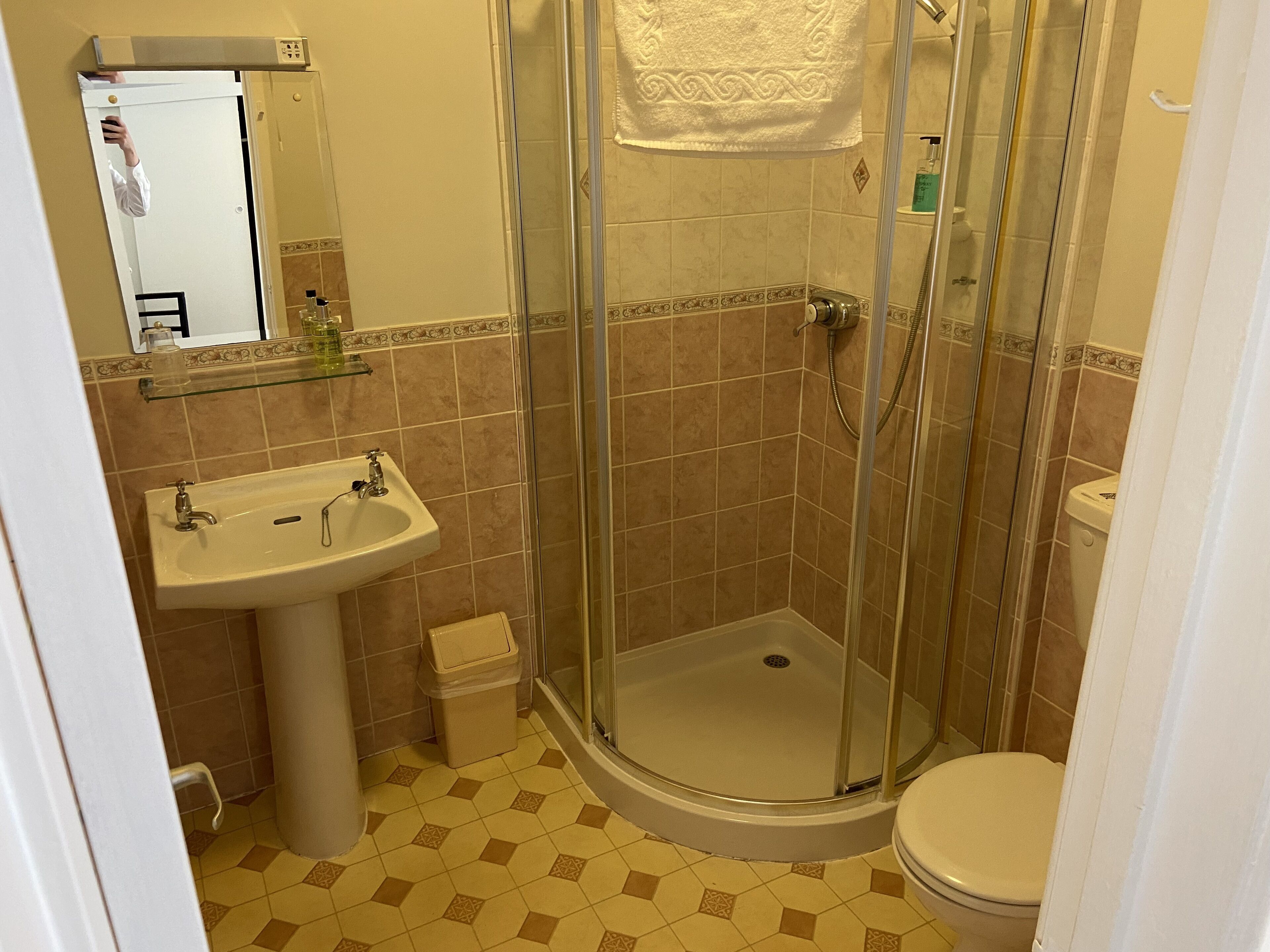 A bathroom with a glass-enclosed shower, a sink, and a toilet.