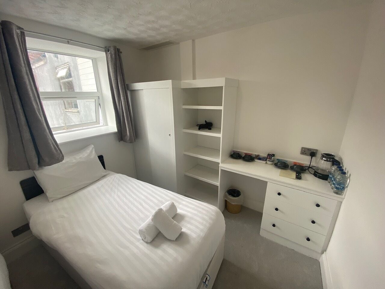Une chambre bien rangée, avec un lit, un bureau et une armoire.