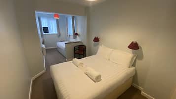 Una habitación de hotel con una cama grande, dos lámparas de noche, una silla, un escritorio y una ventana con cortinas.