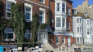 A beachfront apartment building with ivy-covered walls, outdoor seating, and a sign reading "BEACHVIEW APARTMENT". - Fairhaven Hotel (Weymouth)