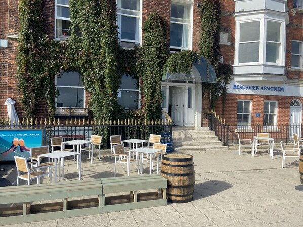 A building with a sign for 'Beachview Apartment' and a cafe named 'Artois' with outdoor seating. - Fairhaven Hotel (Weymouth)