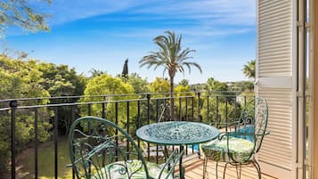 Enjoy a serene view of the lush garden from this balcony, complete with a round table and comfortable seating.