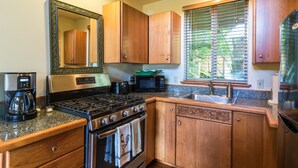 A kitchen with wooden cabinets, a stove, a microwave, and a coffee maker. - Mahina Cottage, Mahina Cottage (Maui County)