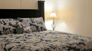 Een bed met een bloemenprint deken en een zwart hoofdeinde.