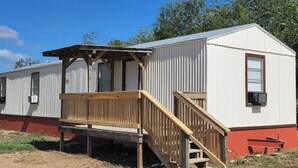 A single-story mobile home with a wooden deck and a ramp leading to the entrance. - "R" - Place on 127 (Sabinal)