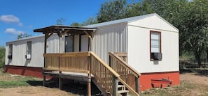 A single-story mobile home with a wooden deck and a ramp leading to the entrance. - "R" - Place on 127 (Sabinal)