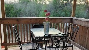 Een houten terras met een tafel en stoelen, omgeven door een houten balustrade.
