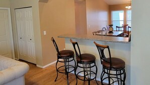 A kitchen with a bar area, two bar stools, a countertop, and a dining table with chairs. - Mountain Retreat w/Foosball/Game Table! Fireplace~Large Deck~Near Park~Dogs OK! (Flagstaff)