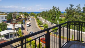 A coastal road with vehicles, a hotel, and shops. - Tal Beach Hotel (Kemer)