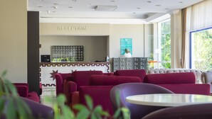 A reception area with a sign, a bulletin board, and a seating area with red sofas. - Tal Beach Hotel (Kemer)