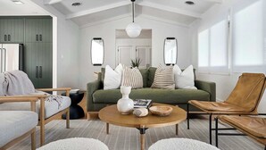 Un salon moderne avec un canapé vert, un fauteuil en cuir et une table basse ronde en bois.