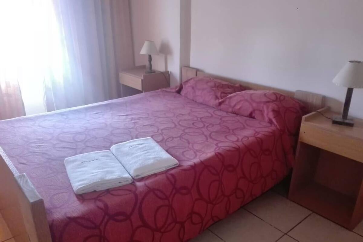 Una cama bien hecha con un edredón estampado y dos toallas dobladas al lado.