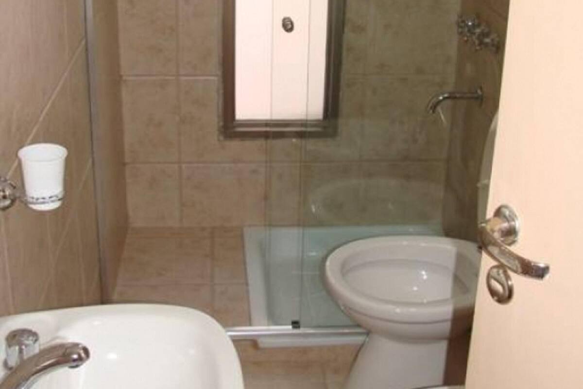 Un baño con cabina de ducha de vidrio, inodoro y lavamanos.