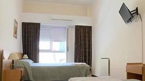 A hotel room with two beds, a desk, a chair, a flat-screen TV mounted on the wall, and an air conditioning unit. - Bet Hotel (Buenos Aires)