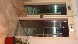 An elevator with a digital display, a potted plant, and a marble floor. - Bet Hotel (Buenos Aires)