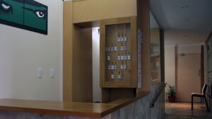 A reception desk with a wooden counter, a wall-mounted keycard dispenser, and a framed artwork above the counter. - Bet Hotel (Buenos Aires)
