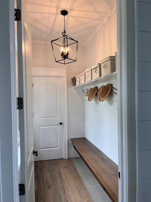 A hallway with a white door, a wooden bench, and storage boxes on the wall.