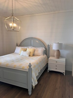 Une chambre à coucher comprenant un lit, une table de chevet, une lampe et un luminaire suspendu.