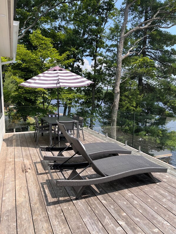 Une terrasse avec une table et des chaises, un fauteuil de relaxation et un parasol à rayures.