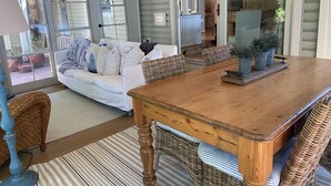 Un salon chaleureux avec une table à manger en bois, des chaises en osier et un canapé blanc.