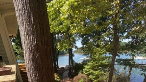 Un escalier en bois mène à une terrasse d’où l’on a une vue sur un lac, le tout étant entouré d’arbres et surplombé par un ciel dégagé.