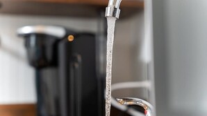 Un lavamanos con agua corriendo, una tetera y una cafetera.