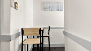 Una habitación de esquina con una mesa y sillas de madera, un cuadro en la pared y un dispositivo de seguridad en la puerta.