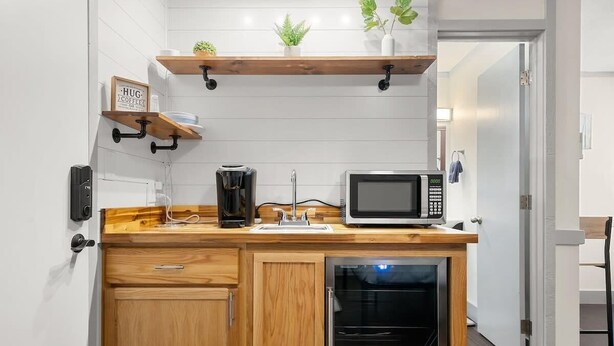 Una kitchenette compacta equipada con microondas, cafetera y armarios de madera.
