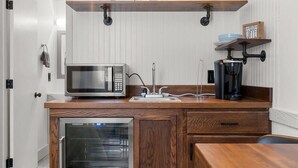 Eine kleine Küchenzeile mit Mikrowelle, Kaffeemaschine und Backofen.