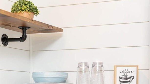Une cuisine équipée d’une machine à café, d’une étagère avec une plante et d’un tableau encadré.