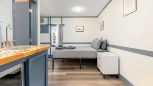 Een kleine slaapkamer met een bed, nachtkastje en een klein kastje.