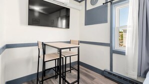 Een kleine keukenhoek met een raam, een klok en een tafel met stoelen.