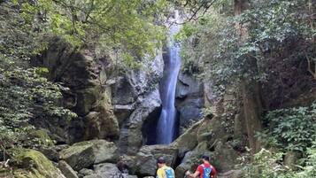 A group of hikers navigating a rocky terrain with a waterfall in the background.