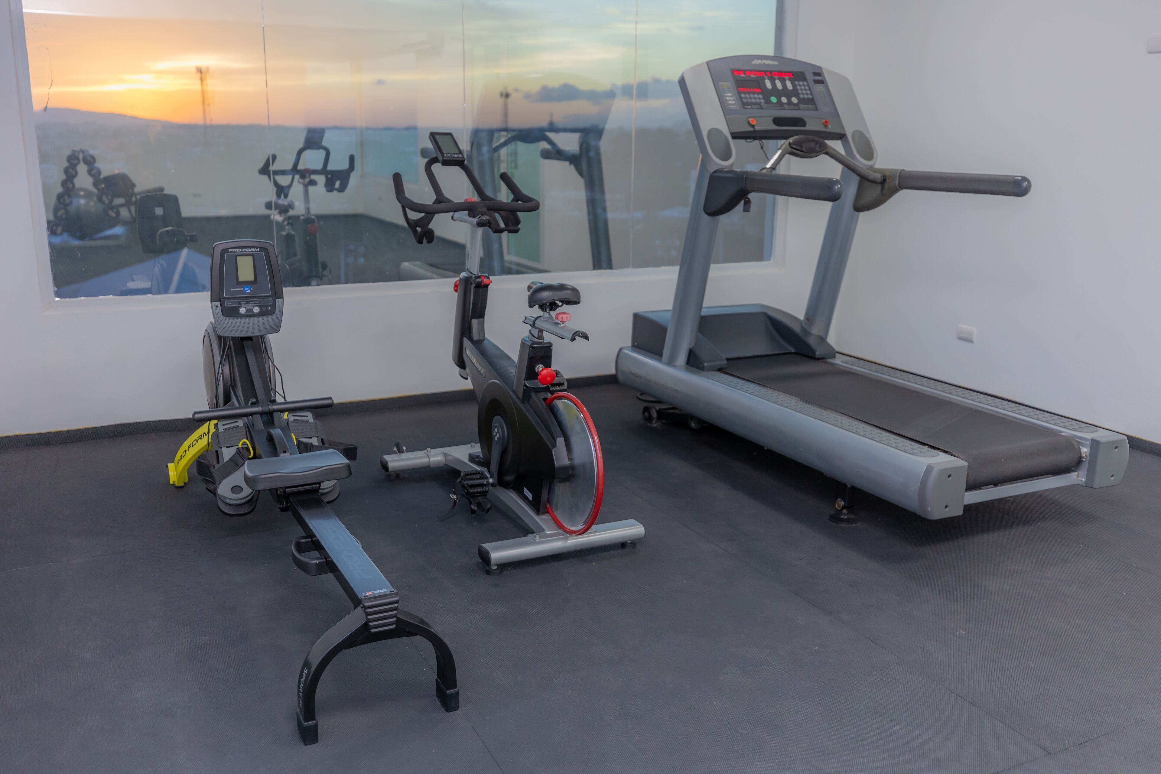 Un gimnasio con bicicleta estática, elíptica y cinta de correr.