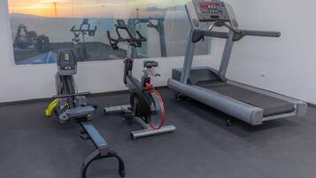 Un gimnasio con bicicleta estática, elíptica y cinta de correr.