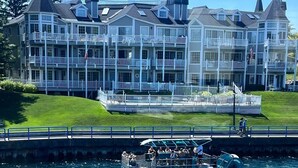 Un hotel frente al mar con varios balcones y un barco amarrado al primer plano.