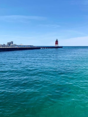 A pier extending into a calm sea with a lighthouse at the end. - Full Kitchen & Laundry in Large Condo- Very Clean! (Charlevoix)