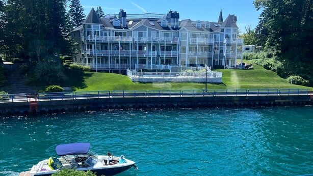 Hotel frente al agua con varios balcones, un muelle y un bote.