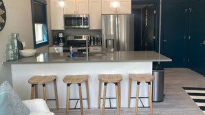 Una cocina moderna con una isla central, electrodomésticos de acero inoxidable y taburetes de madera.