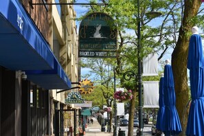 Une rue où se trouvent divers commerces, notamment une friterie spécialisée dans le poisson blanc et un magasin de vêtements.