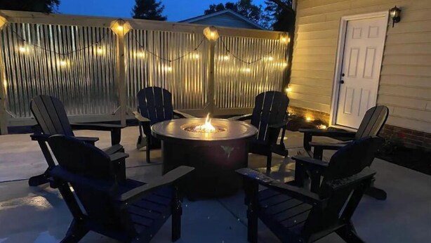 An outdoor patio with a circular fire pit surrounded by four chairs. - Peak Comfort of Apex (Apex)