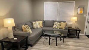 A living room with a grey sofa, two side tables with lamps, and a glass coffee table. - Peak Comfort of Apex (Apex)