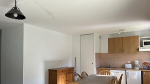 Una cocina compacta con armarios de madera, una mesa de comedor con sillas y un microondas.
