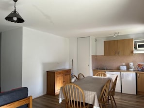 Cozy room with a kitchenette area, dining table, and comfortable seating for four.