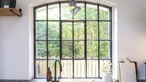 A kitchen with a large window, a sink, and a cutting board. - Beautiful Home in Heart of Truro (Truro)