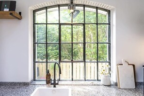 A kitchen with a large window, a sink, and a cutting board. - Beautiful Home in Heart of Truro (Truro)